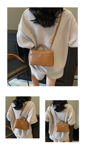 Detail of a brown quilted handbag with top handle and silver hardware zippers