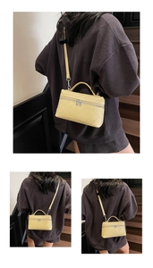 Detail of light yellow quilted crossbody bag with dual metal zippers and silver hardware
