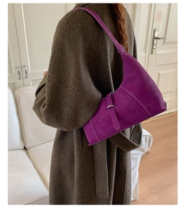 Detailed close-up of a purple half-moon shoulder bag with matte texture and silver buckle