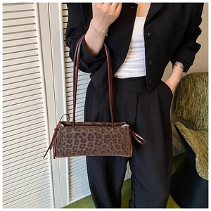 Detail of leopard print handbag showing drawstring side knots and slim shoulder strap