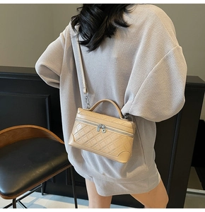 Detailed view of apricot quilted leather handbag with silver chain strap and top handle