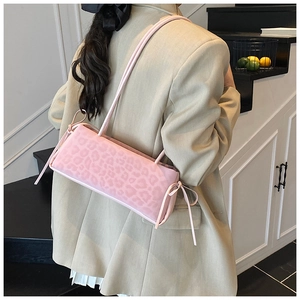 Pink leopard print shoulder bag with decorative bows shown in a stylish fashion lifestyle setting