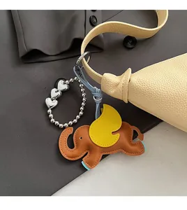 Detail of creative leather elephant bag charm with yellow wings on a lychee grain handbag