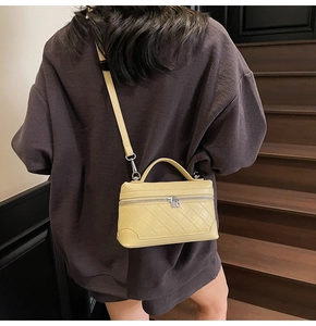 Detail of a bright yellow quilted shoulder bag worn by a model on wooden stairs