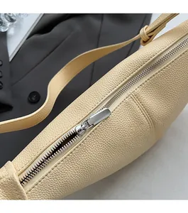 Close-up of smooth silver zipper and lychee pattern leather texture on beige crossbody bag