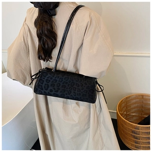Detail of black leopard print shoulder bag featuring textured fabric and side knot design