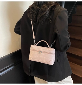 Detail of pink faux leather crossbody bag featuring quilted texture and dual zippers