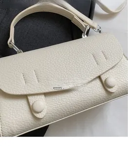Dettaglio ravvicinato della borsa in pelle bianca crema con grana di litchi