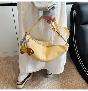 Detail of pale yellow lychee leather crescent bag with adjustable strap and elephant charm