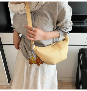 Detail of yellow lychee texture dumpling bag featuring elephant charm on wide shoulder strap