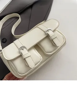 Detail of cream leather messenger bag with soft texture and silver buckle front pockets