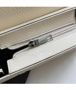Dettaglio della cerniera in metallo argentato su borsa in pelle martellata beige