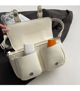 Detailed view of the off-white crossbody bag with dual front pockets and metal snaps