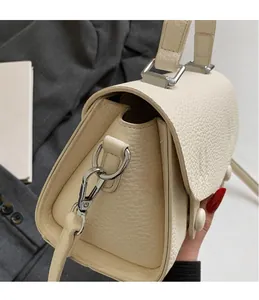 Dettaglio del gancio argentato e della pelle martellata litchi su una borsa beige