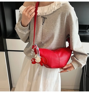 Detail of red pebbled leather half-moon crossbody bag with cute elephant charm