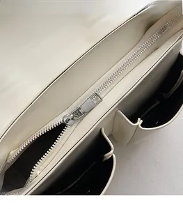 Detailed view of smooth silver metal zipper and interior compartments on shoulder bag