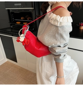 Red pebbled leather hobo bag with elephant charm shown on a model in a modern kitchen
