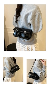 Détail du sac à bandoulière noir brillant rétro avec boucles argentées et poches