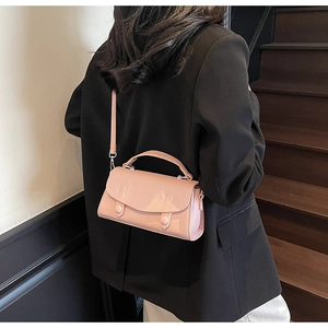 Pink lychee texture crossbody bag shown styled with a black blazer on model stairs