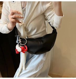 Detail of black croissant bag featuring red elephant charm and silver heart bead chain