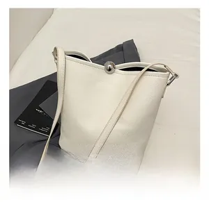 Détail du sac seau en cuir grainé blanc avec fermoir boule en métal argenté élégant