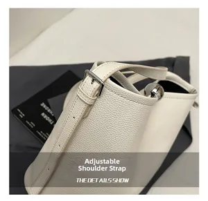 Détail de la bandoulière réglable avec boucle en métal sur un sac seau en cuir blanc