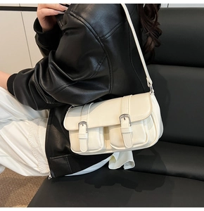 Detailed view of off-white shoulder bag with double buckle pockets and silver metal hardware