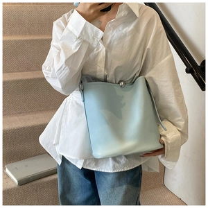 Détail du sac seau bleu clair avec fermoir à boule argentée sur cuir texturé grainé