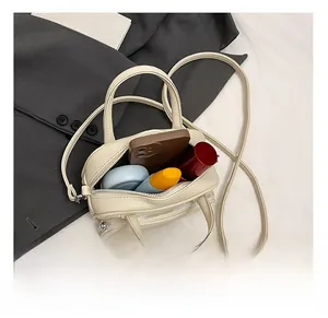 Interior view showing capacity of cream litchi texture crossbody pillow bag with daily items