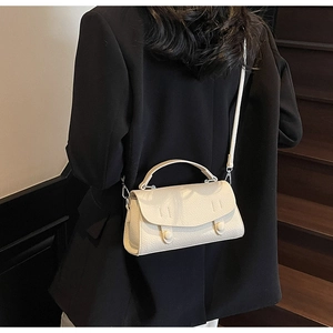 Dettaglio della borsa in pelle martellata bianco crema con fibbie decorative tonde