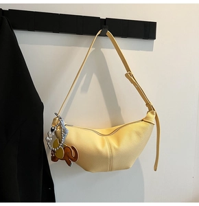 Detail view of yellow hobo bag with pebble leather texture and elephant charm