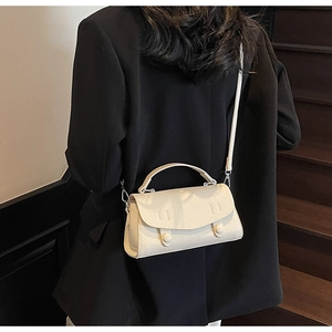 Detail of minimalist beige lychee texture leather crossbody bag with curved flap