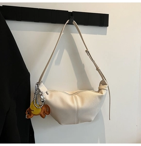 Detail view of cream crescent bag featuring a stylized leather elephant bag charm accessory