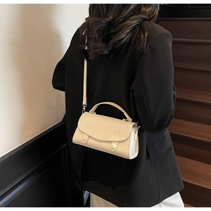 Detail of cream pebbled leather crossbody bag showing texture and detachable shoulder strap