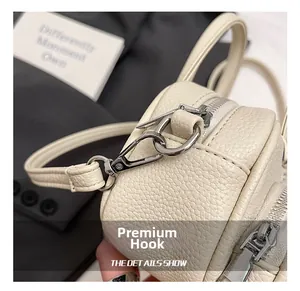 Detail of silver metal hook and zipper on creamy lychee textured crossbody bag