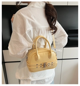 Détail du sac Boston jaune avec doubles boucles et garnitures métalliques argentées