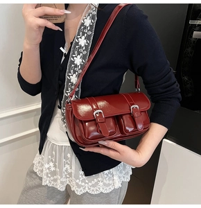 Detail of burgundy leather shoulder bag with vintage silver buckles and dual front pockets