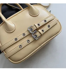 Détail du sac à main beige en cuir avec boucles argentées et sangles à œillets