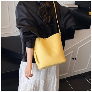 Détail d'un sac seau jaune à motif litchi avec fermoir magnétique à bille argentée