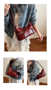 Dettaglio borsa a mezzaluna rosso scuro con cerniere argentate e stile minimalista