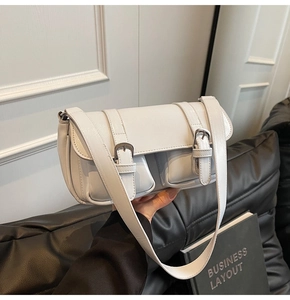 Close-up of white leather underarm bag with silver buckles and dual front pockets