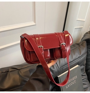 Detail of dark red glossy leather shoulder bag with two front pockets and silver buckles