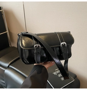 Detailed shot of black oily leather shoulder bag with vintage silver double buckles