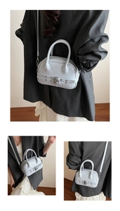 Détail du sac à bandoulière gris clair avec œillets métalliques et lanières décoratives