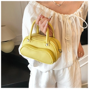 Detail of yellow lychee texture leather handbag with dual handles and zipper pocket