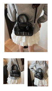 Détail d'un sac à main noir brillant avec boucle de ceinture et œillets métalliques