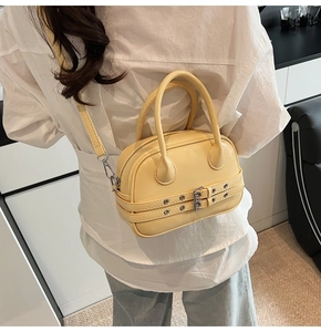 Détail du sac bandoulière jaune crème avec boucles argentées et double poignée ronde