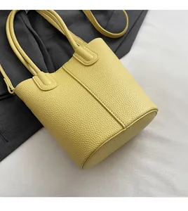 Detailed close-up of vibrant yellow bucket bag showing premium lychee pattern leather texture