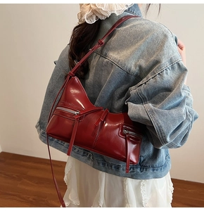 Dettaglio borsa in pelle lucida bordeaux con zip argento e lungo tiretto in pelle