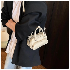 Close-up of cream Boston bag with lychee texture and silver metal hooks on shoulder strap